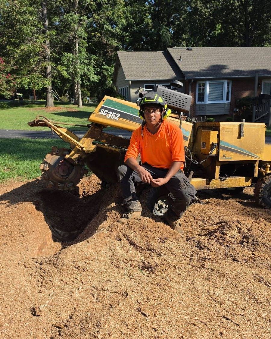 JC Tree Services crew member next to a stump grinder after grinding a stump